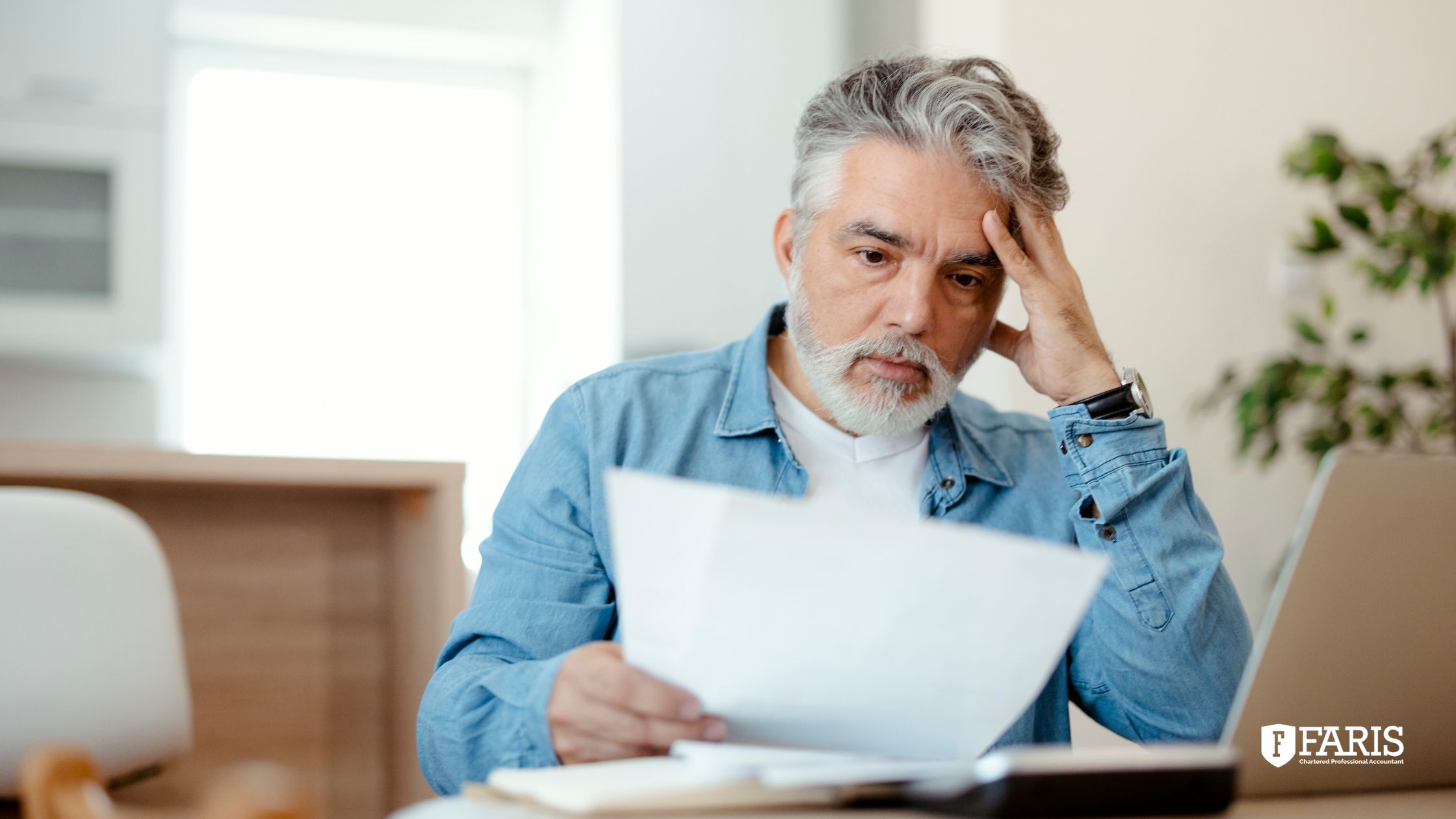 Concerned man reviewing financial paperwork at home related to allowable business investment loss and tax reporting.