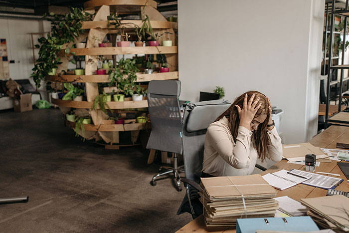 A woman trying to file tax returns holds her head in her hands