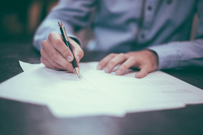 A person filling out multiple forms at a desk