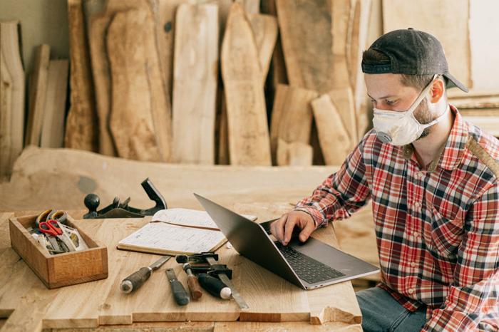 Man in a wood shop using a laptop