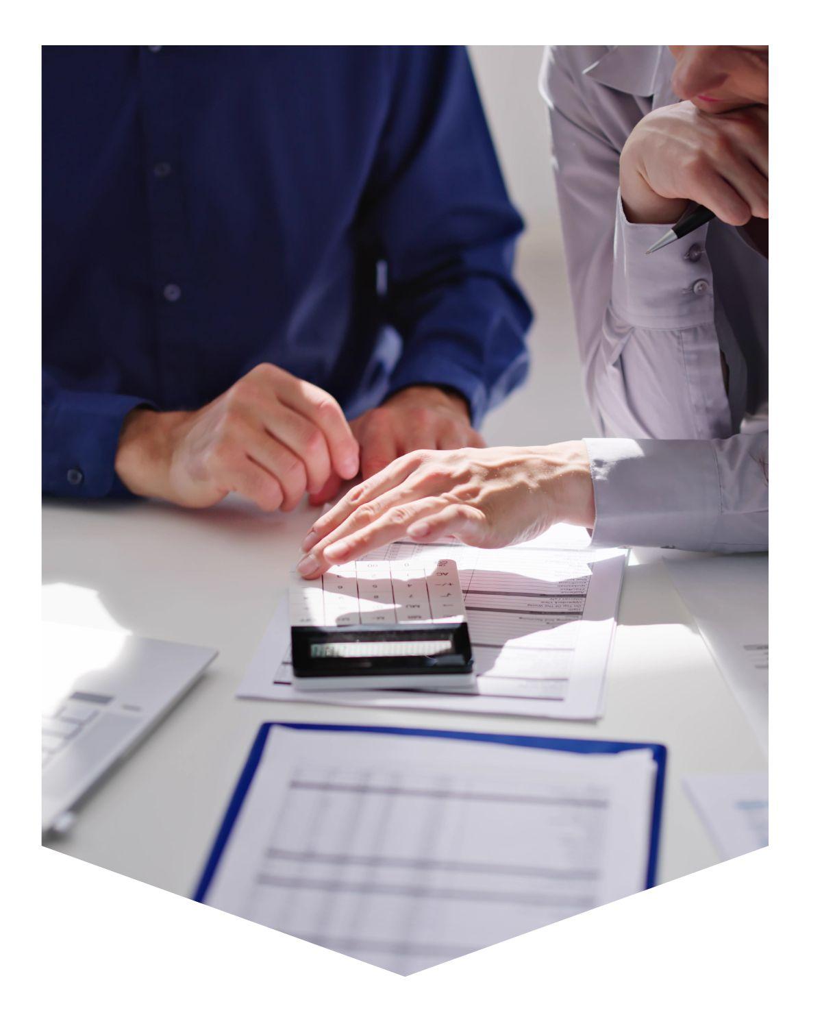 Two people sitting at a desk with papers and calculator