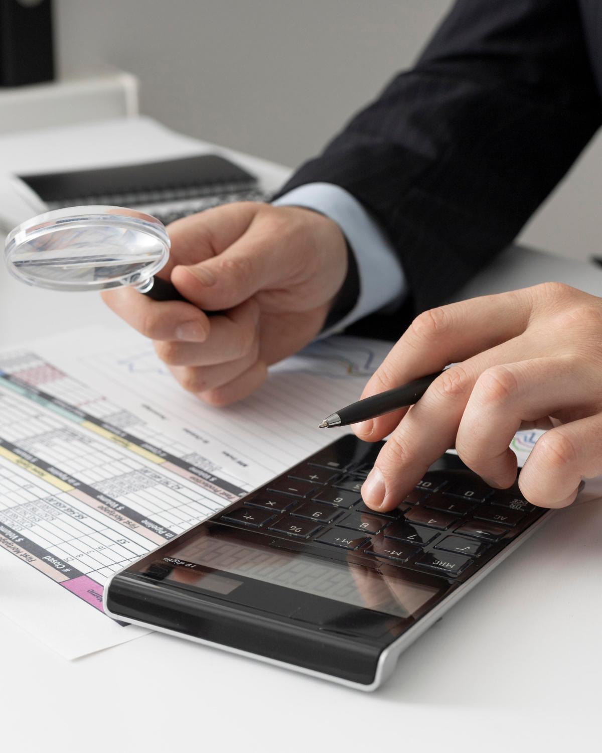 Person using calculator with financial sheets in front of them