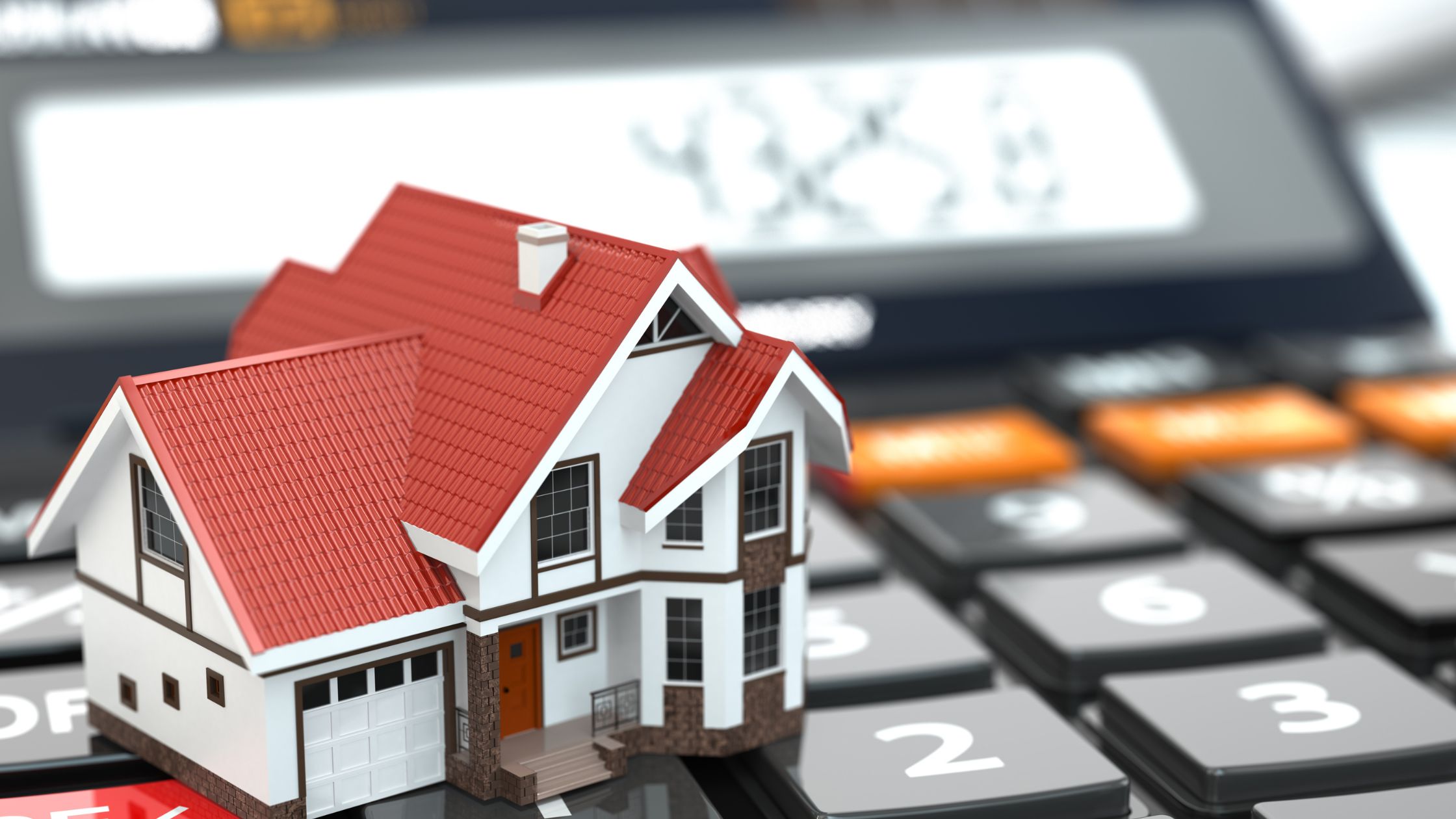 Model house on a calculator symbolizing Canadian real estate and Underused Housing Tax calculations.